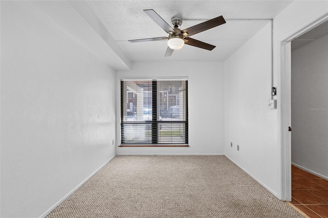 carpeted empty room featuring a textured ceiling, a ceiling fan, and baseboards