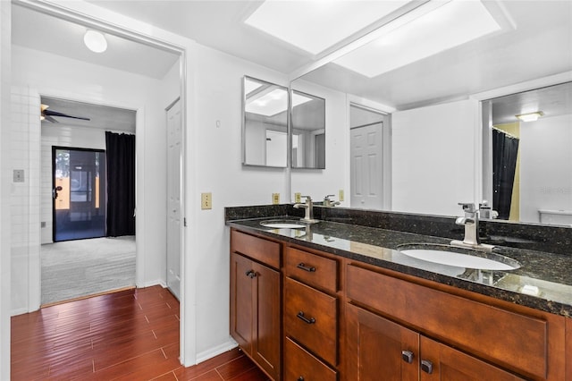 bathroom with double vanity, ceiling fan, a sink, and wood finished floors