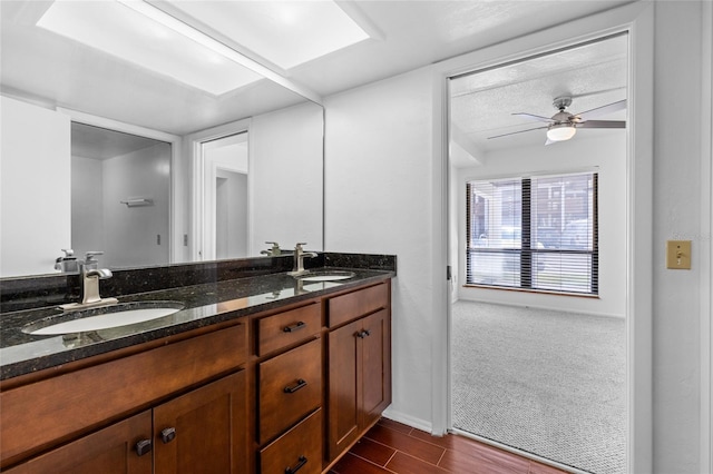 bathroom with double vanity, a sink, a ceiling fan, and baseboards