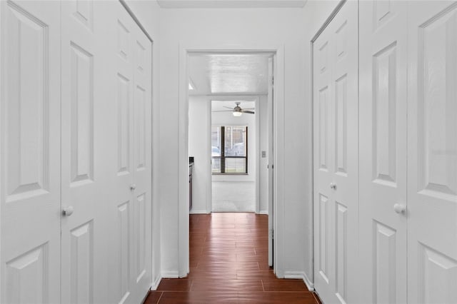 hallway featuring dark wood-style floors, a textured ceiling, and baseboards