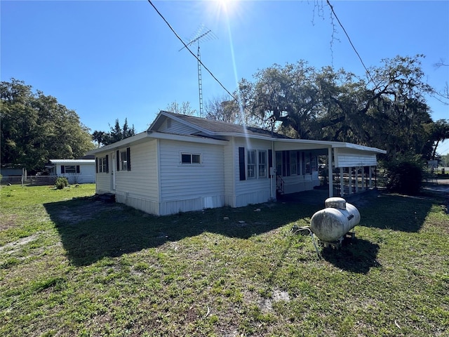 view of side of property with a carport and a lawn