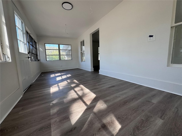 empty room with dark wood-type flooring and baseboards