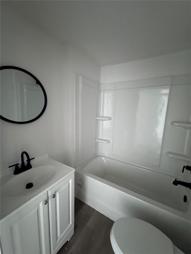 bathroom with toilet, washtub / shower combination, wood finished floors, and vanity