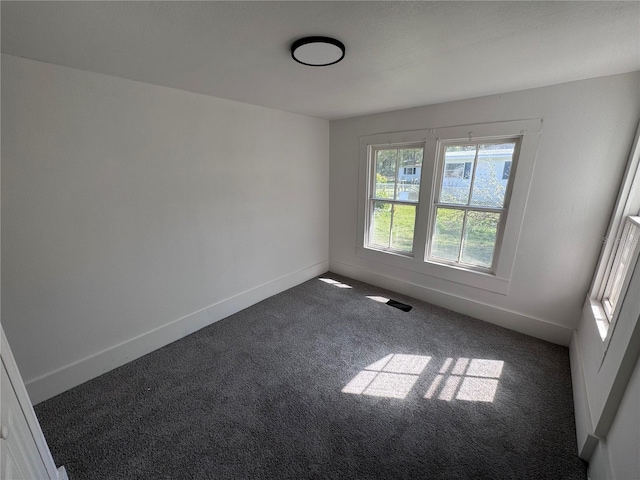 carpeted spare room featuring visible vents and baseboards