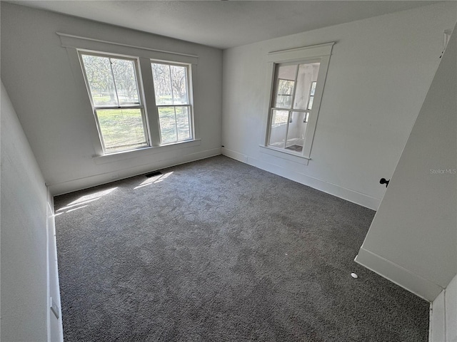 carpeted empty room with visible vents, baseboards, and a wealth of natural light