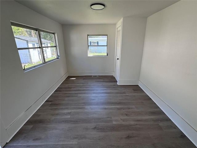 spare room featuring dark wood finished floors, a wealth of natural light, and baseboards