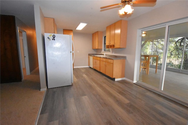 kitchen with white appliances, light brown cabinets, baseboards, and a sink