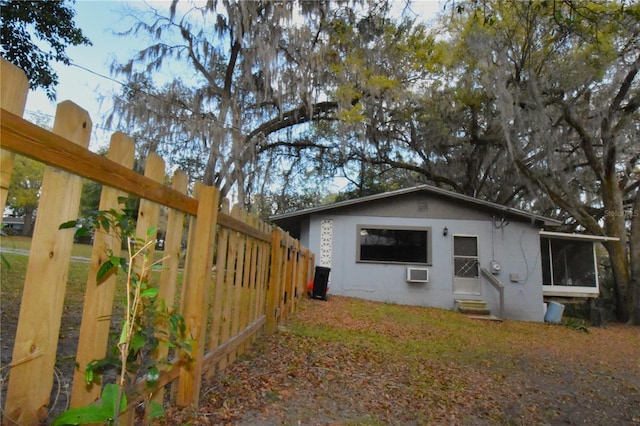 back of property featuring entry steps, fence, an AC wall unit, and stucco siding