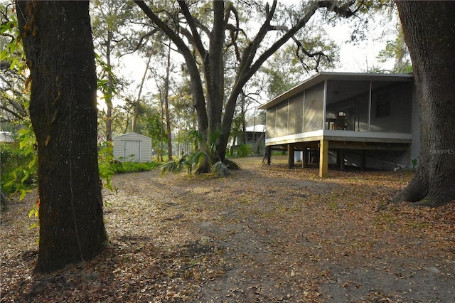 view of yard with a sunroom, a storage unit, and an outbuilding