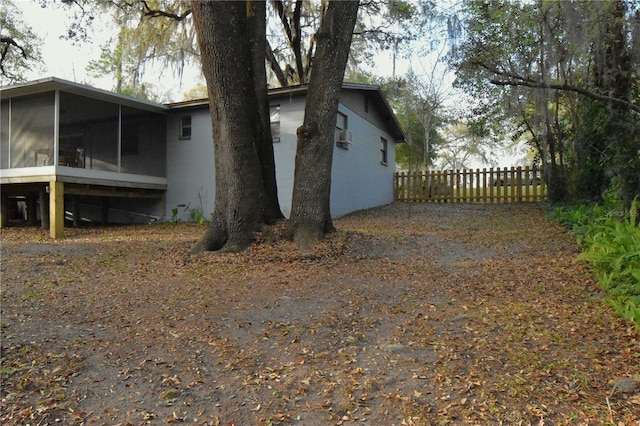 view of side of property with fence and a sunroom