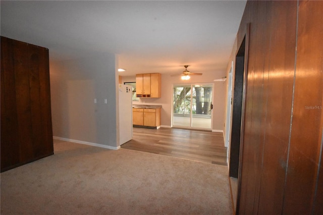 unfurnished living room with light carpet, baseboards, and a ceiling fan