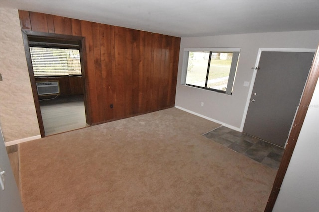 unfurnished room with wood walls, carpet flooring, and a wall mounted air conditioner