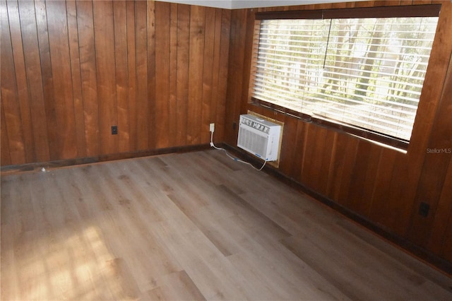 unfurnished room featuring a wall mounted air conditioner, wood finished floors, and wooden walls