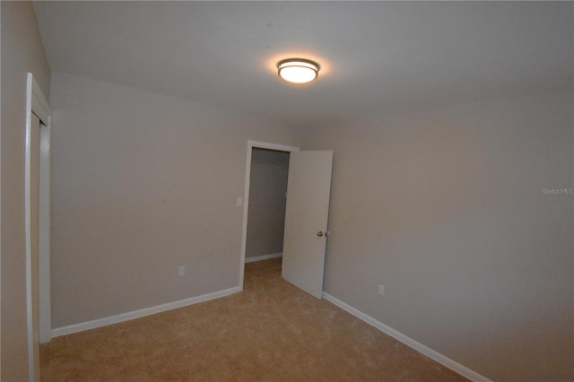 spare room featuring light carpet and baseboards