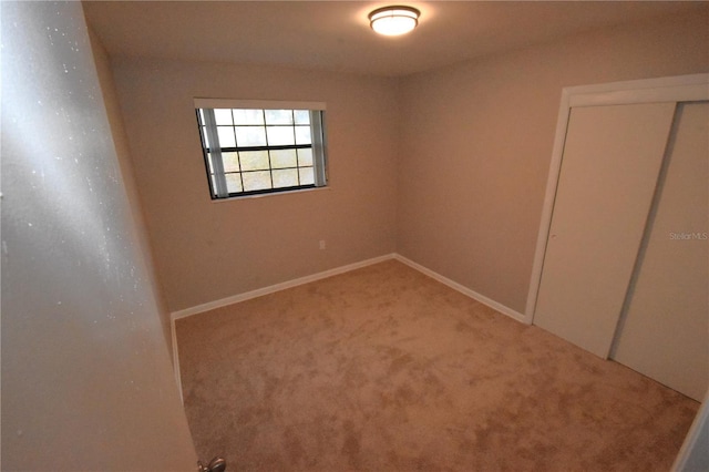 carpeted spare room featuring baseboards