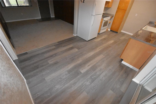 kitchen with white appliances, wood finished floors, and baseboards