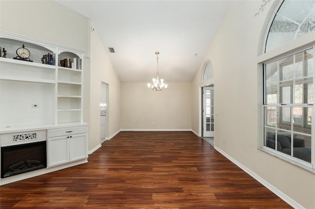 interior space with high vaulted ceiling, dark wood-type flooring, a fireplace, and an inviting chandelier