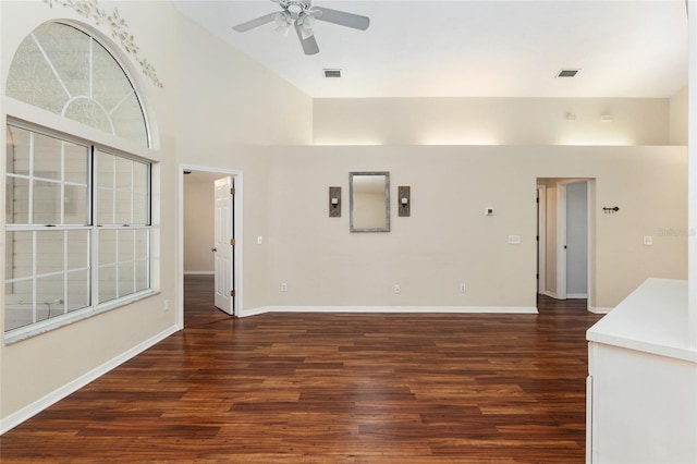 unfurnished room featuring ceiling fan, wood finished floors, a towering ceiling, and baseboards