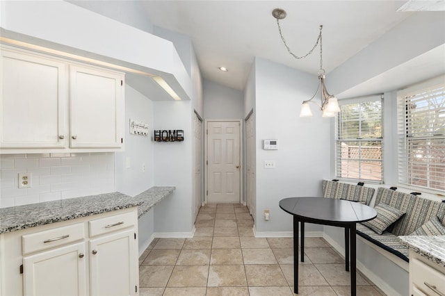 kitchen with breakfast area, white cabinets, light stone counters, and decorative backsplash