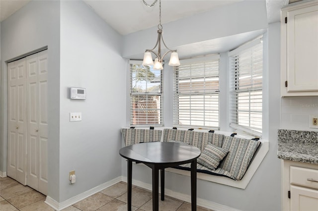 dining room featuring breakfast area, light tile patterned flooring, an inviting chandelier, and baseboards