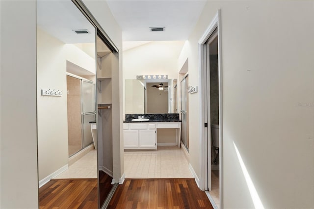 hallway featuring a sink, visible vents, and wood finished floors