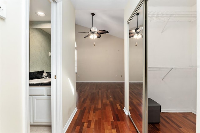 hall featuring lofted ceiling, a sink, baseboards, and wood finished floors