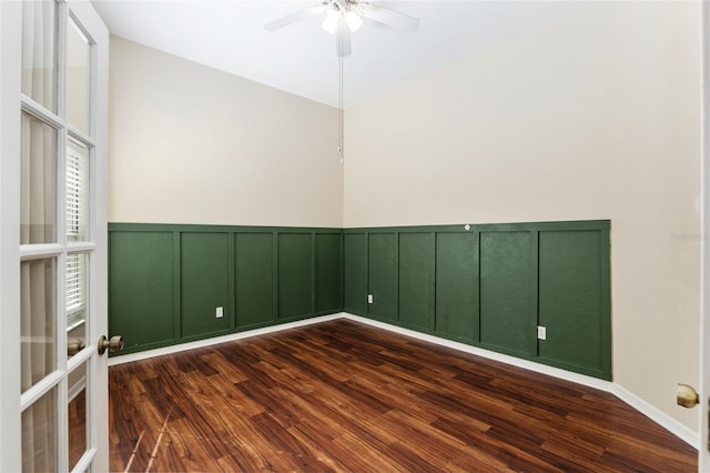 unfurnished room featuring ceiling fan, dark wood-style flooring, a wainscoted wall, and a decorative wall