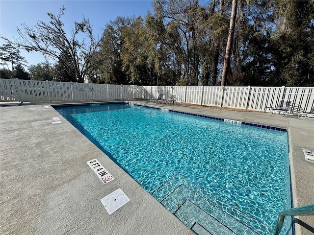 community pool with a patio area and fence