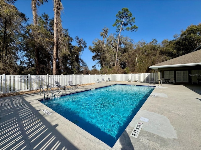 pool with a patio area and fence