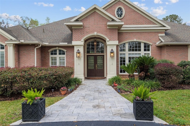 view of front of home featuring french doors, brick siding, and a shingled roof