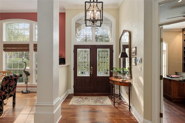 foyer entrance with an inviting chandelier, hardwood / wood-style flooring, french doors, a towering ceiling, and crown molding