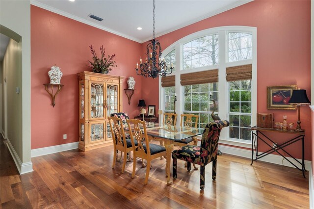 dining room featuring visible vents, wood finished floors, arched walkways, crown molding, and baseboards