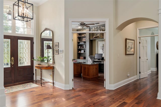 entryway featuring arched walkways, french doors, dark wood-type flooring, and baseboards