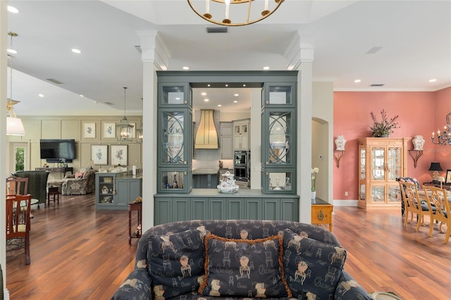 living room featuring visible vents, an inviting chandelier, wood finished floors, and crown molding