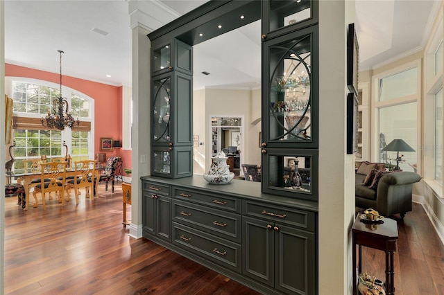 bar featuring dark wood-style floors, a chandelier, crown molding, and baseboards