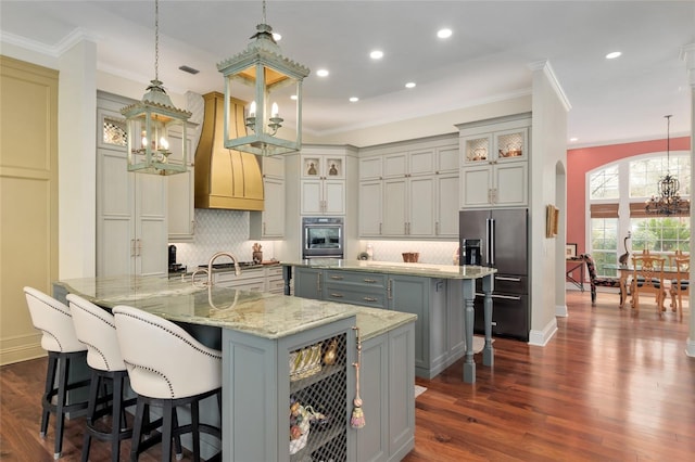 kitchen featuring gray cabinets, arched walkways, a large island, appliances with stainless steel finishes, and a chandelier