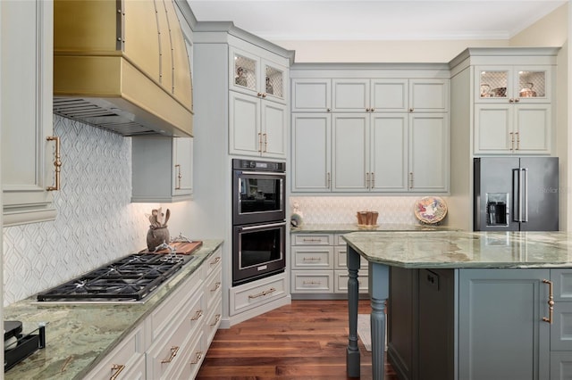 kitchen with dark wood-style floors, stainless steel appliances, glass insert cabinets, and premium range hood