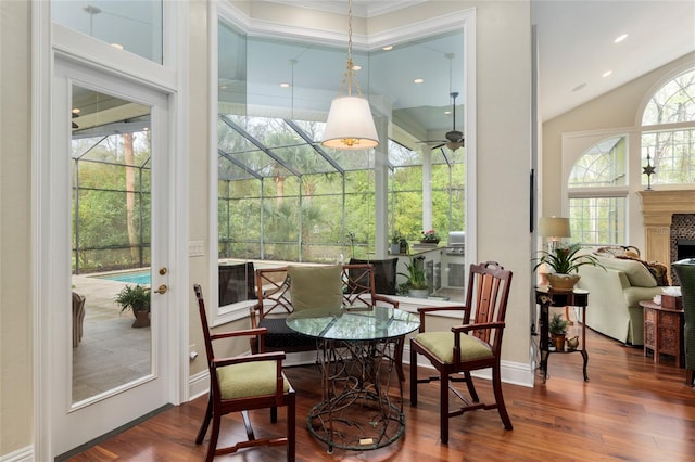 dining space with wood finished floors, recessed lighting, a high ceiling, a fireplace, and ceiling fan