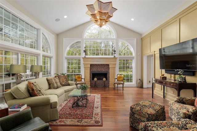 living area with a fireplace, high vaulted ceiling, and wood finished floors