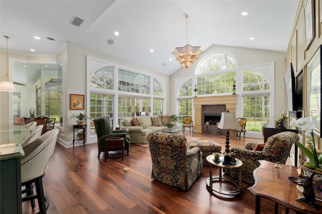 living area with visible vents, high vaulted ceiling, dark wood-style floors, a fireplace, and a chandelier