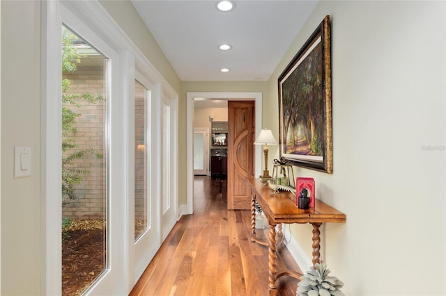 hall featuring recessed lighting, baseboards, and light wood finished floors