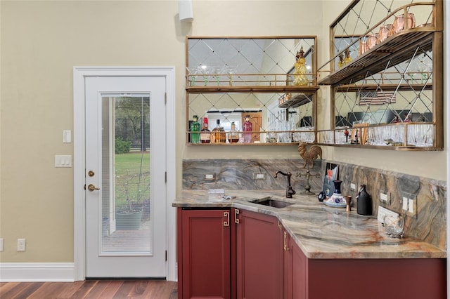 bar featuring wet bar, dark wood-style floors, baseboards, and a sink