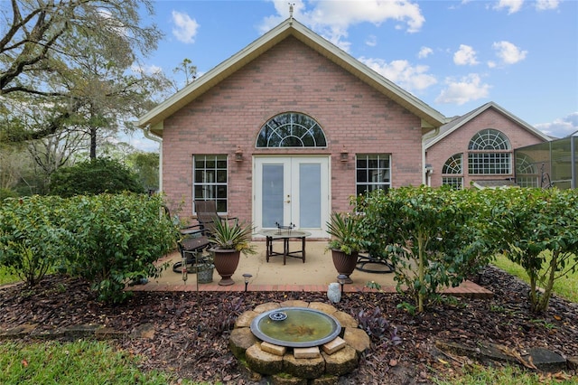 view of front of house featuring brick siding, french doors, and a patio