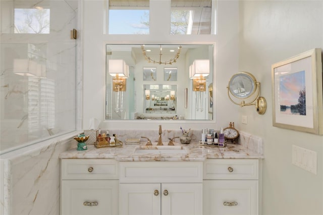 full bath with a marble finish shower and vanity