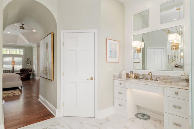 ensuite bathroom with vanity, a ceiling fan, baseboards, and marble finish floor