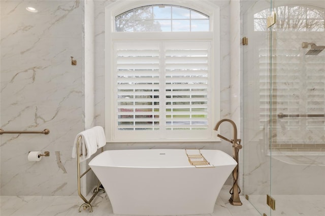 bathroom with a marble finish shower, a soaking tub, a healthy amount of sunlight, and marble finish floor