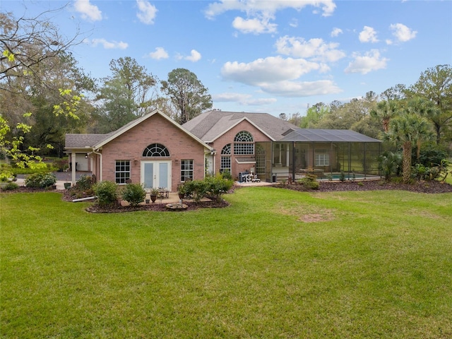 rear view of property featuring brick siding, a lawn, and glass enclosure