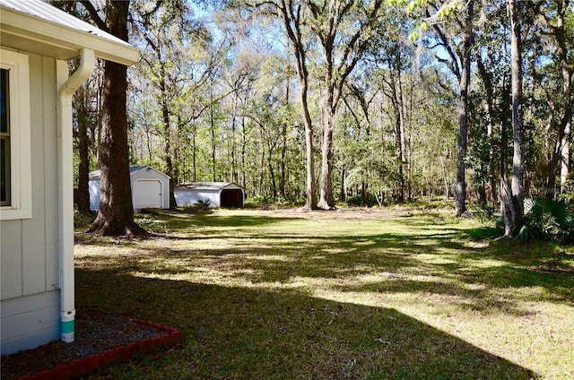 view of yard with a garage, a view of trees, an outdoor structure, and dirt driveway