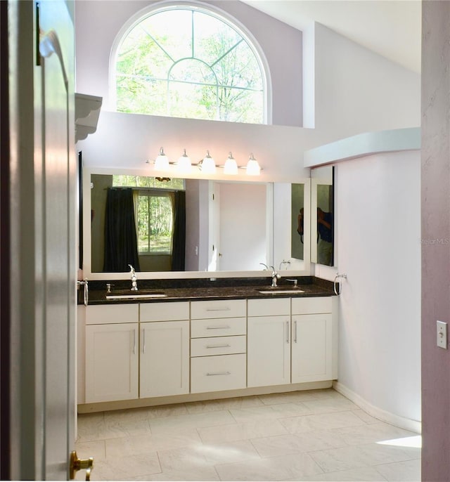 full bath featuring double vanity, high vaulted ceiling, and a sink