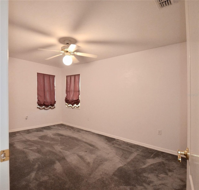 spare room featuring visible vents, dark carpet, baseboards, and ceiling fan